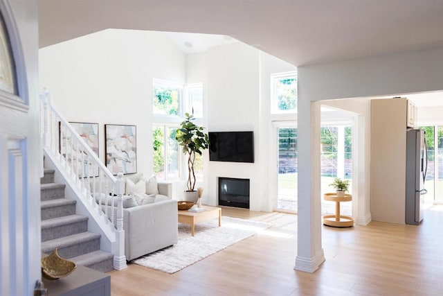 14879 Heather Glen Way, San Diego, CA 92128 - living area featuring light wood-style flooring, stairway, a glass covered fireplace, and high vaulted ceiling
