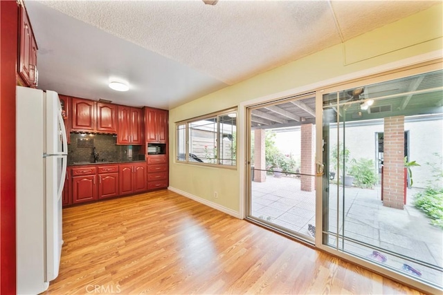 1840 S Summer Pl, West Covina, CA 91792 - kitchen featuring freestanding refrigerator, light wood-style flooring, baseboards, reddish brown cabinets, and dark countertops