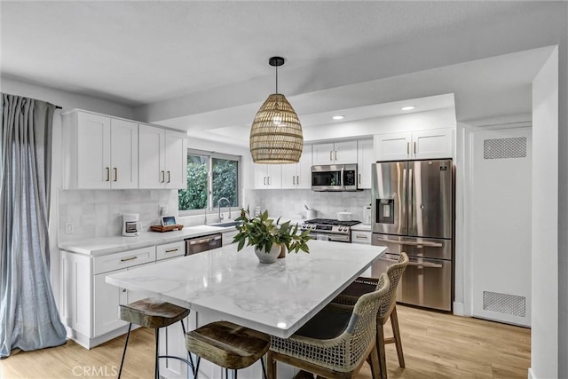 1 Vista Del Ponto, San Clemente, CA 92672 - kitchen with light wood-style flooring, white cabinetry, a kitchen breakfast bar, tasteful backsplash, and appliances with stainless steel finishes