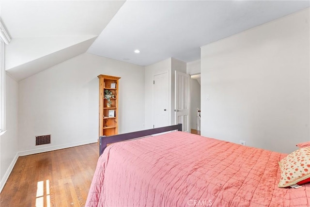 bedroom with wood finished floors, visible vents, recessed lighting, vaulted ceiling, and baseboards