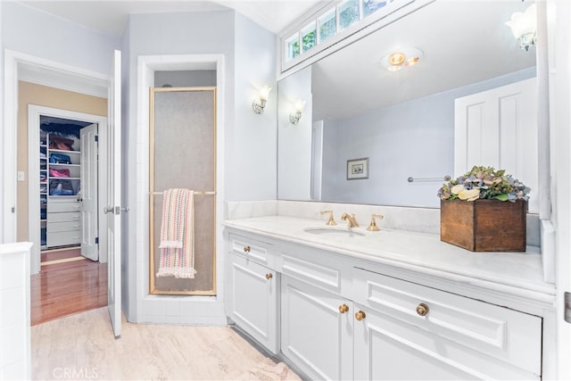 bathroom with a shower stall, vanity, and a walk in closet