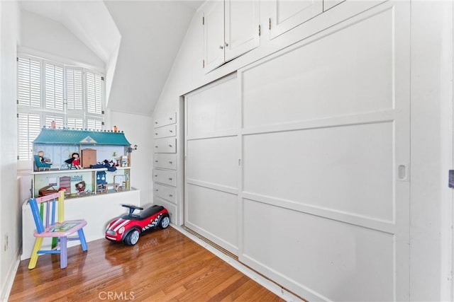 recreation room featuring vaulted ceiling and wood finished floors