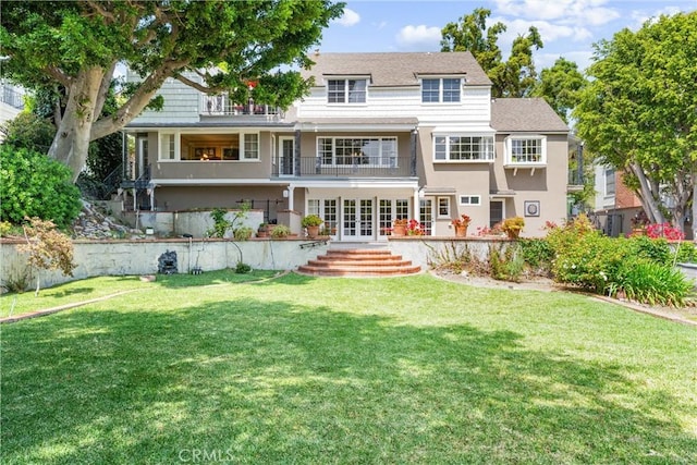 back of house featuring a yard, stucco siding, french doors, and a balcony