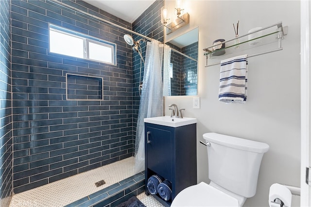 bathroom with vanity, toilet, and tiled shower