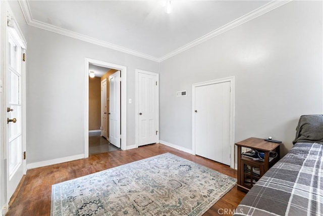 bedroom featuring crown molding, visible vents, wood finished floors, and baseboards