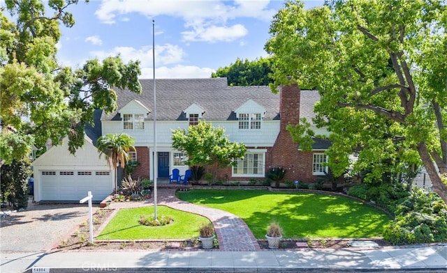 view of front facade featuring brick siding, a chimney, a front yard, and a detached garage