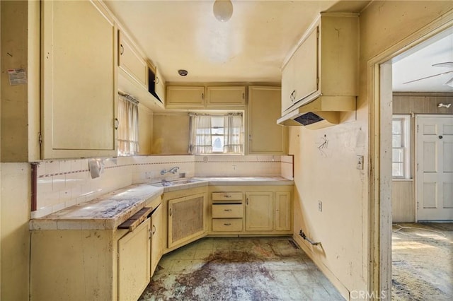 kitchen featuring backsplash, tile counters, light brown cabinetry, and a sink