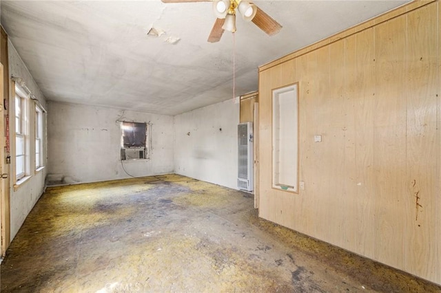 spare room with concrete floors, a heating unit, a ceiling fan, and cooling unit