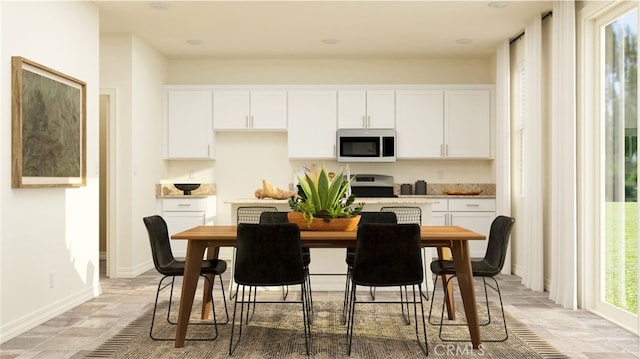 kitchen with light countertops, white cabinets, stone finish flooring, and range