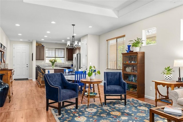 living area featuring a chandelier, light wood-style flooring, baseboards, and recessed lighting