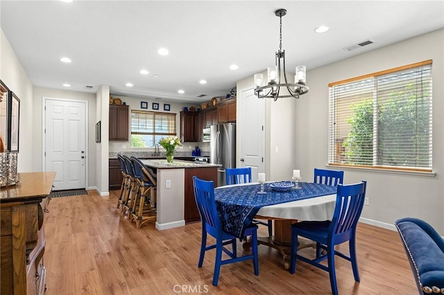 dining space with a notable chandelier, light wood-style flooring, recessed lighting, baseboards, and visible vents