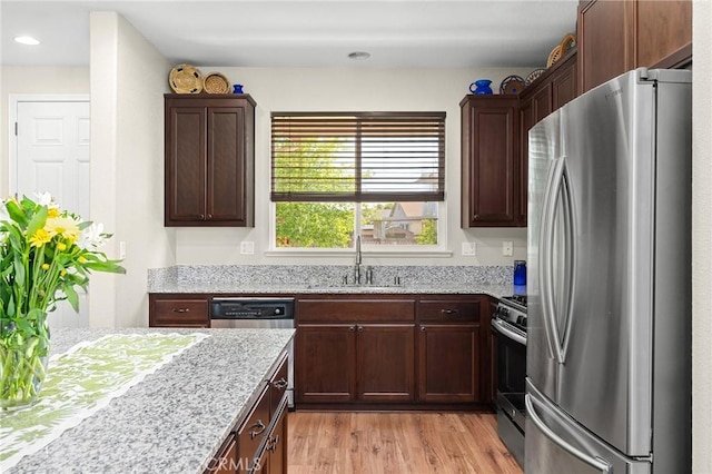 kitchen featuring a sink, stainless steel appliances, light wood-type flooring, light stone counters, and recessed lighting
