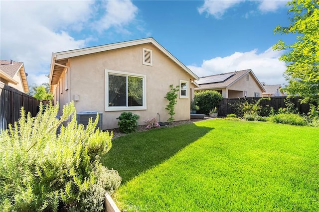 back of house with a yard, stucco siding, a fenced backyard, and central air condition unit