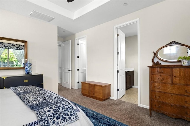 bedroom featuring baseboards, ensuite bath, visible vents, and light colored carpet