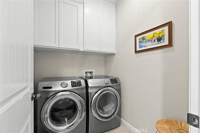 washroom featuring washing machine and clothes dryer, baseboards, and cabinet space