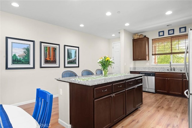 kitchen featuring dark brown cabinetry, appliances with stainless steel finishes, a center island, and light wood-type flooring