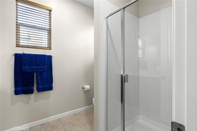 bathroom featuring a stall shower, tile patterned flooring, baseboards, and toilet