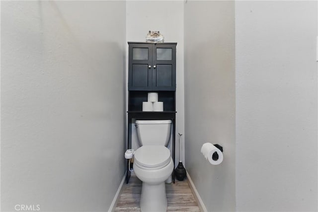 bathroom featuring toilet, baseboards, and wood finished floors