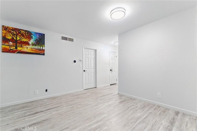 unfurnished room with baseboards, visible vents, and wood finished floors