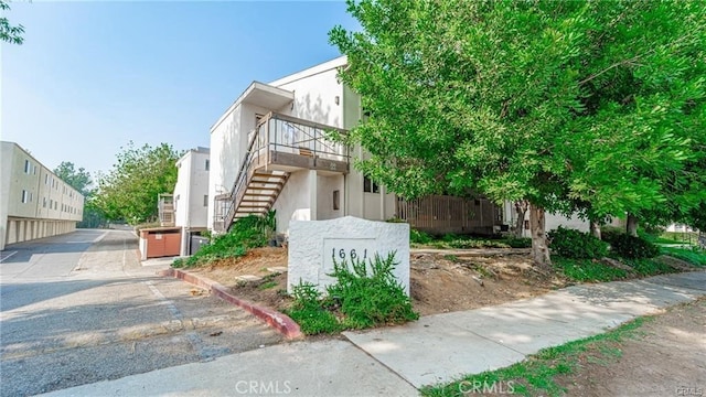 view of home's exterior featuring stairway, stucco siding, and uncovered parking