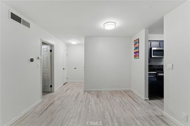 empty room featuring baseboards, visible vents, and wood finished floors