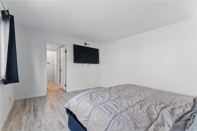 bedroom with visible vents, wood finished floors, and baseboards