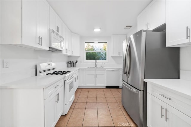 kitchen featuring white cabinets, light tile patterned floors, visible vents, and white appliances