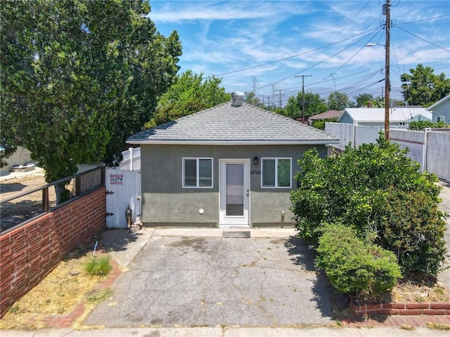 bungalow-style house featuring a shingled roof, stucco siding, a gate, and fence