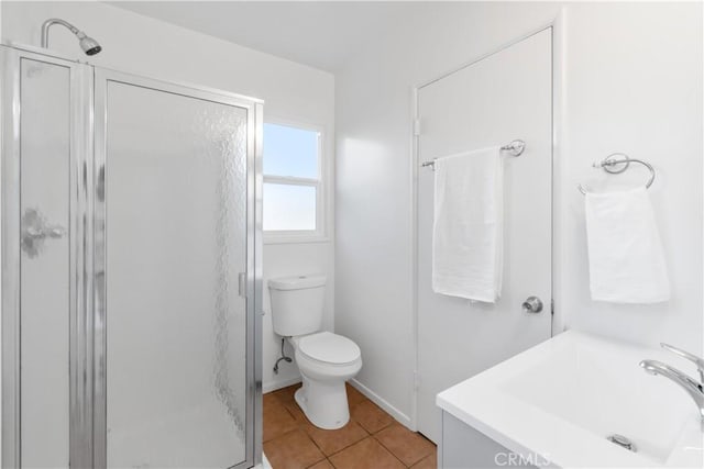 bathroom with toilet, vanity, a stall shower, tile patterned flooring, and baseboards