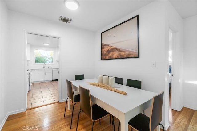 dining room featuring light wood finished floors, baseboards, and visible vents