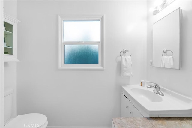 bathroom featuring toilet, baseboards, and vanity