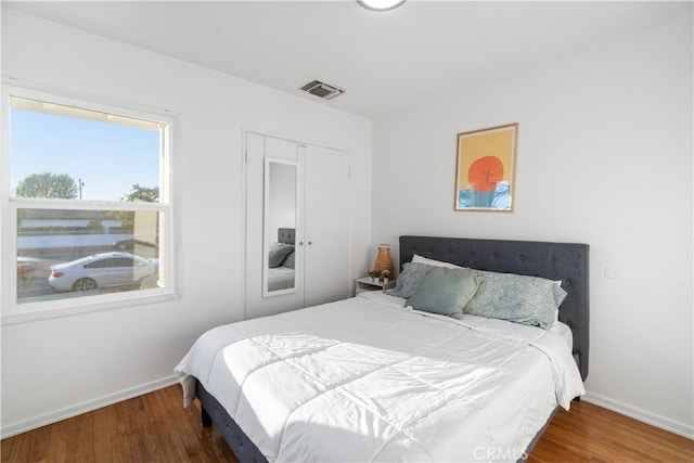 bedroom with baseboards, visible vents, and wood finished floors