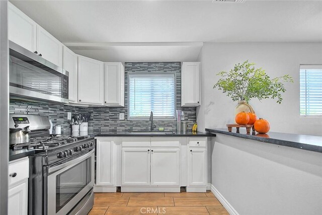 1261 W 13th St, San Bernardino, CA 92411 - kitchen with a sink, stainless steel appliances, tasteful backsplash, white cabinets, and dark countertops