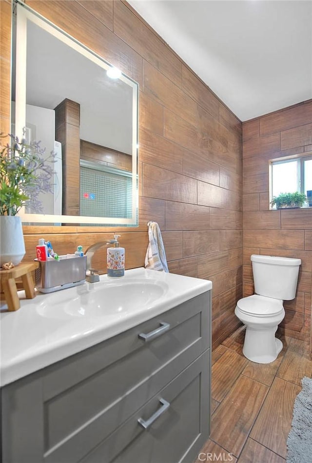 1261 W 13th St, San Bernardino, CA 92411 - bathroom with tile walls, toilet, wood walls, and vanity