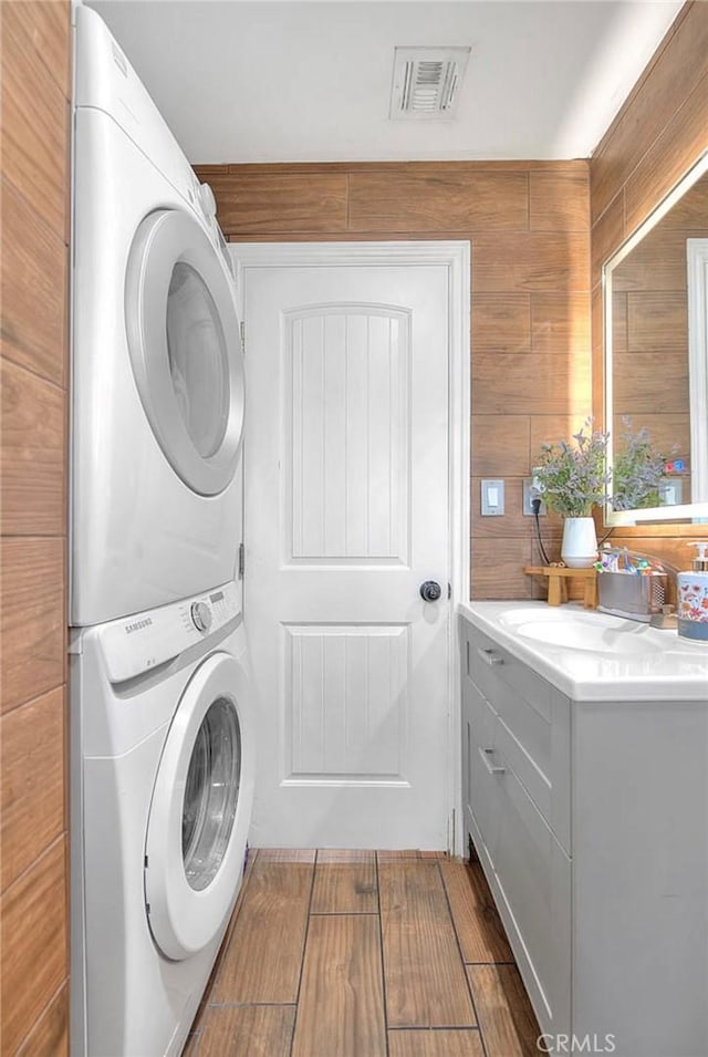 1261 W 13th St, San Bernardino, CA 92411 - washroom with stacked washer and dryer, cabinet space, visible vents, and dark wood-style floors