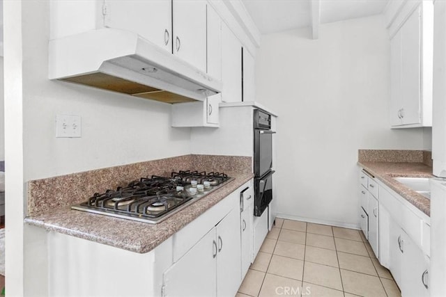 kitchen with light tile patterned floors, white cabinetry, a warming drawer, under cabinet range hood, and stainless steel gas stovetop