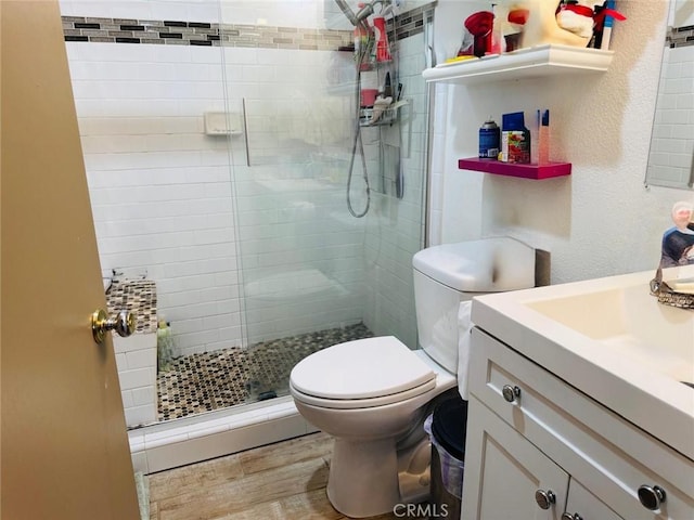 bathroom featuring a stall shower, vanity, toilet, and wood finished floors