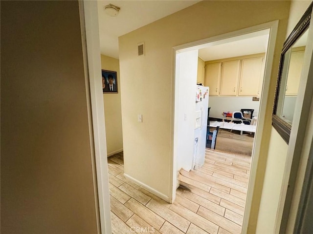 hallway featuring visible vents, baseboards, and wood tiled floor