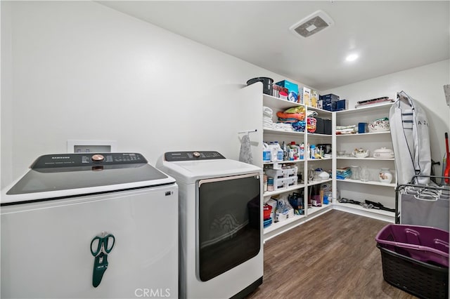 clothes washing area with laundry area, visible vents, wood finished floors, and washing machine and dryer