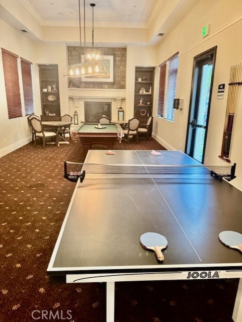 game room featuring a tray ceiling, ornamental molding, and built in shelves