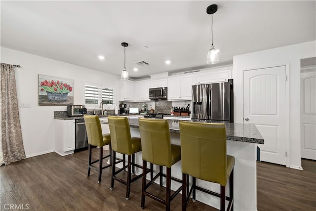 kitchen featuring stainless steel appliances, visible vents, dark wood-style flooring, a center island, and white cabinets
