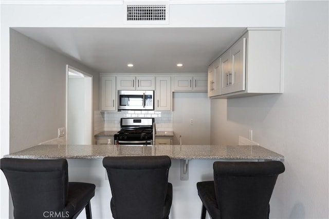 315 W Alameda Ave Unit 6, Burbank, CA 91506 - kitchen with stainless steel appliances, a peninsula, tasteful backsplash, light stone counters, and recessed lighting