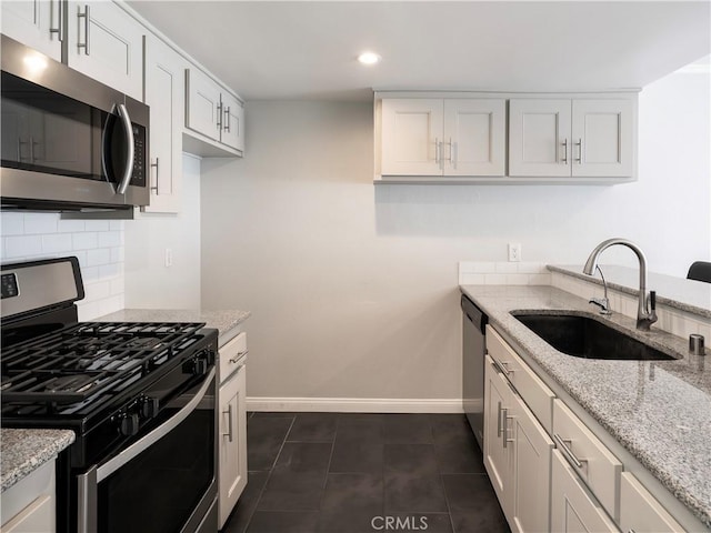 kitchen with decorative backsplash, stainless steel appliances, light stone countertops, and a sink