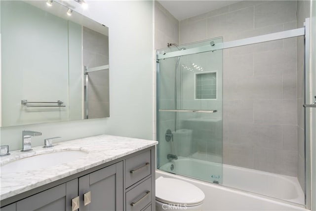 bathroom with toilet, vanity, and combined bath / shower with glass door