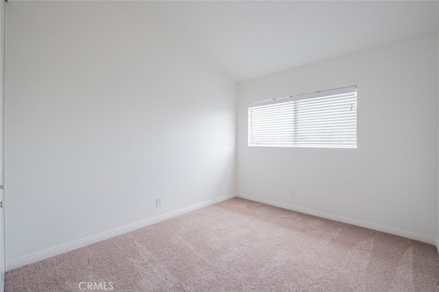 spare room featuring baseboards and light carpet