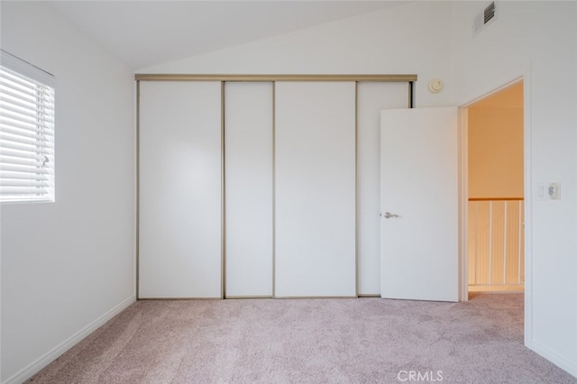 unfurnished bedroom featuring vaulted ceiling, carpet flooring, a closet, and visible vents