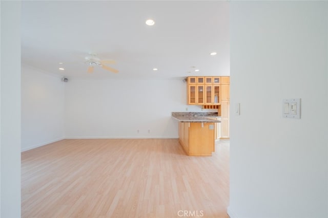kitchen featuring a peninsula, recessed lighting, light wood-style flooring, and glass insert cabinets