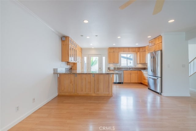 kitchen featuring light wood-type flooring, baseboards, a peninsula, and appliances with stainless steel finishes