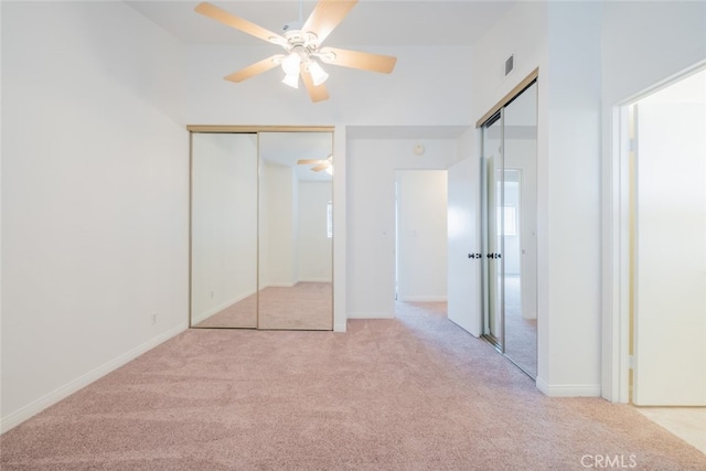 unfurnished bedroom featuring a ceiling fan, baseboards, visible vents, multiple closets, and carpet floors