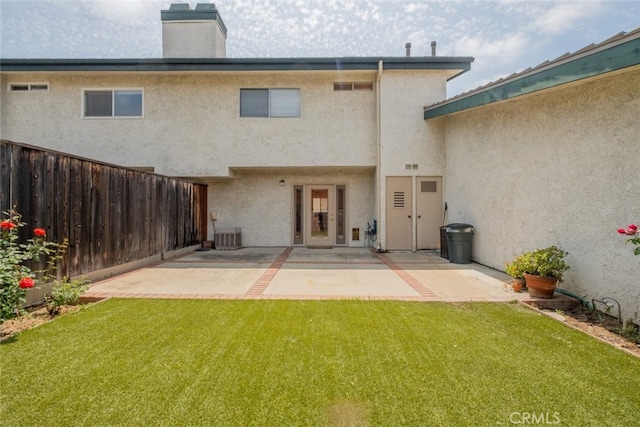 rear view of property with a yard, stucco siding, fence, and a chimney